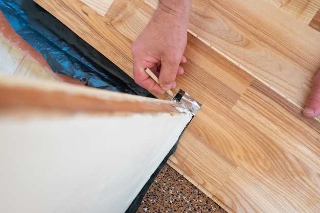 Caucasian man installing wood parquet board during flooring work