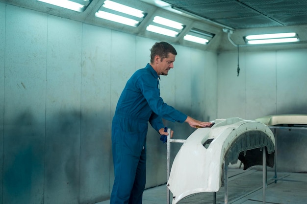 Caucasian man is cleaning car parts before spraying color in repair mechanic painting shop