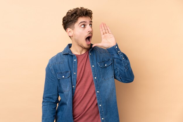 Caucasian man isolated on beige wall shouting with mouth wide open