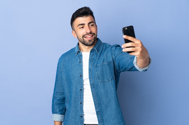 Caucasian man over isolated blue background making a selfie