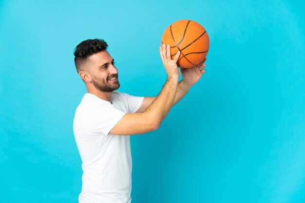 Caucasian man isolated on blue background playing basketball