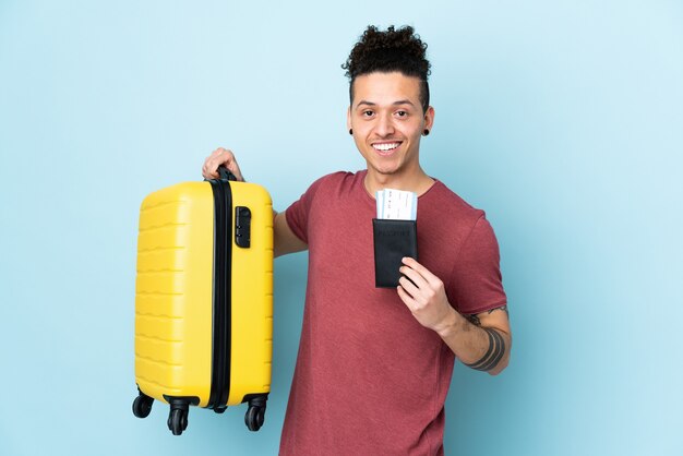 Caucasian man over isolated blue background in vacation with suitcase and passport