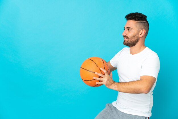 Caucasian man isolated on blue playing basketball