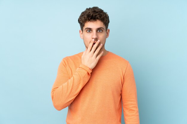 Caucasian man isolated on blue wall surprised and shocked while looking right