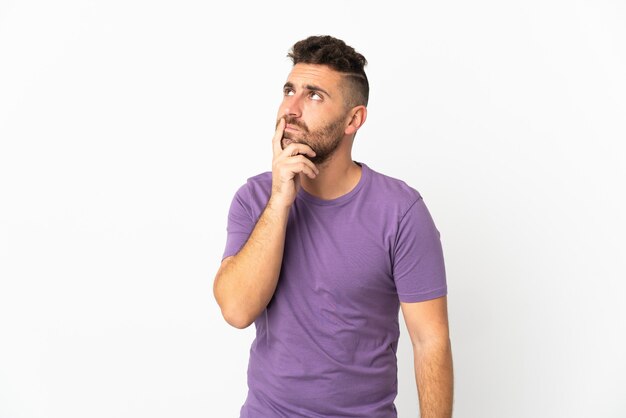 Caucasian man isolated on white background having doubts while looking up