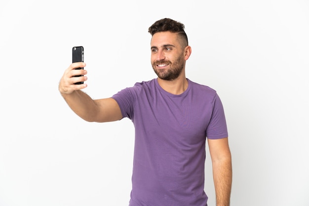 Caucasian man isolated on white wall making a selfie