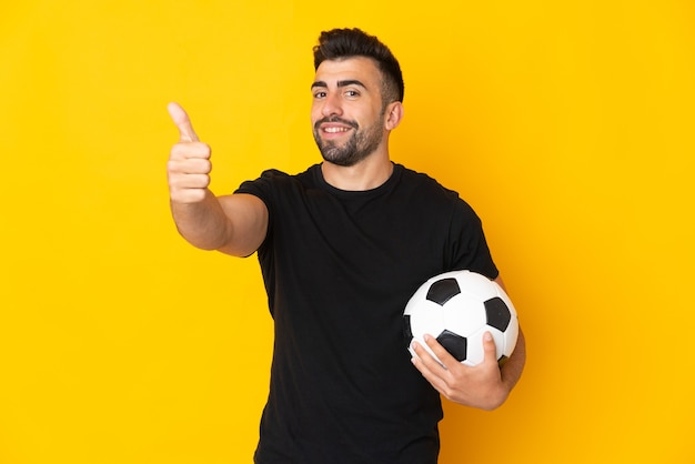 Caucasian man isolated with soccer ball and with thumb up