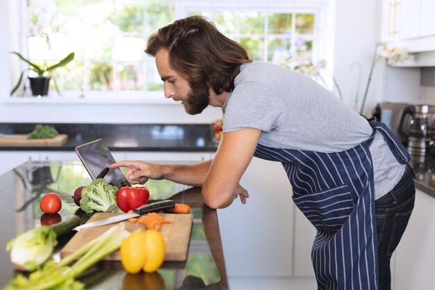 Photo caucasian man in kitchen wearing apron and using tablet