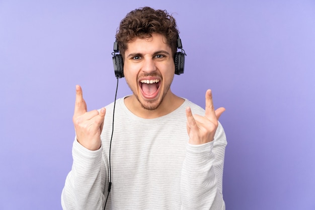 Caucasian man listening music making rock gesture