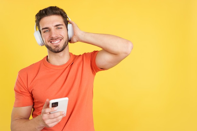 Кавказский мужчина слушает музыку в наушниках и на мобильном телефоне