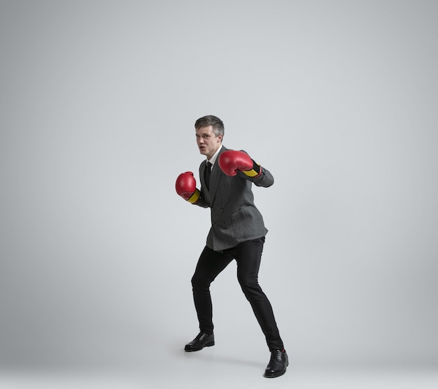 Caucasian man in office clothes boxing isolated on grey  wall