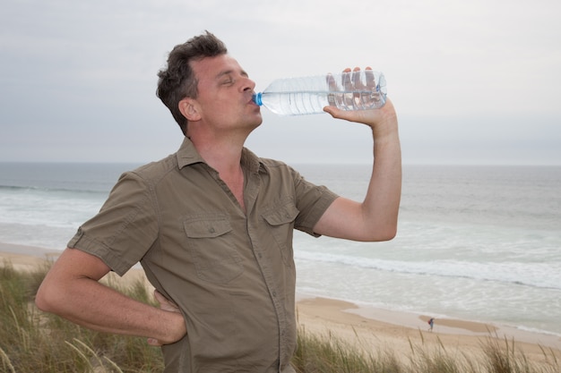 Caucasian man posing at the beach - drinking water good for health