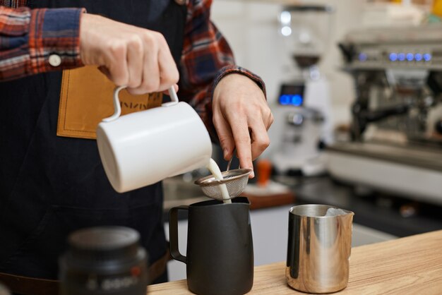 Photo caucasian man pouring hot milk in coffee
