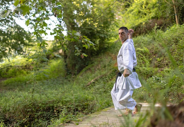 Foto uomo caucasico che pratica karate in una foresta