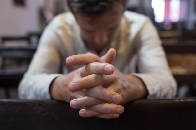 Uomo caucasico che prega in chiesa ha problemi e chiede aiuto a dio