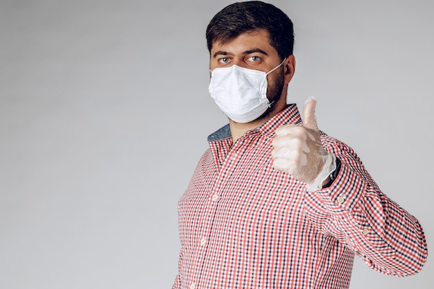 Caucasian man protecting from the coronavirus with a mask and gloves giving a thumbs up