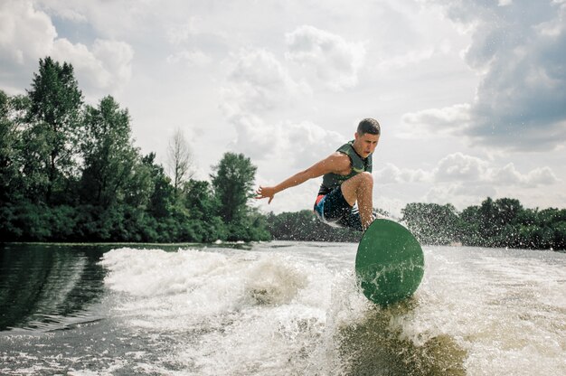 Caucasian man rides the waves by stylish wakeboard