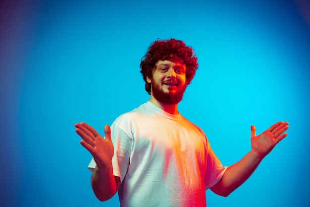 Photo caucasian man's portrait isolated on blue studio background in neon light