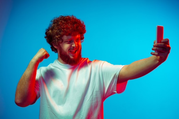 Photo caucasian man's portrait isolated on blue studio background in neon light