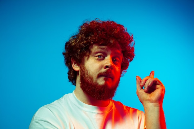 Caucasian man's portrait isolated on blue studio background in neon light