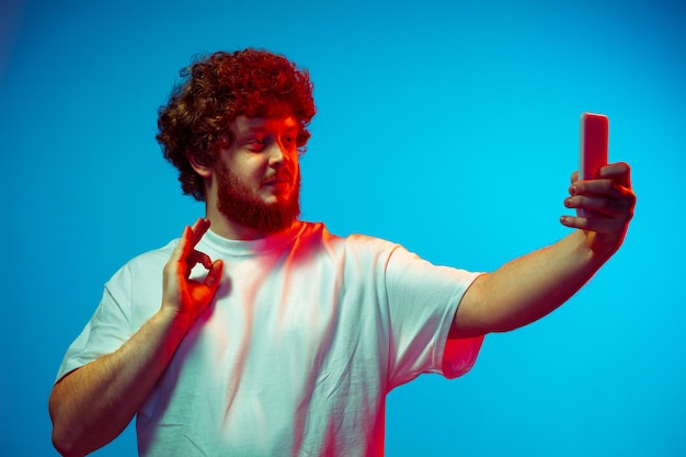 Caucasian man's portrait isolated on blue studio background in neon light