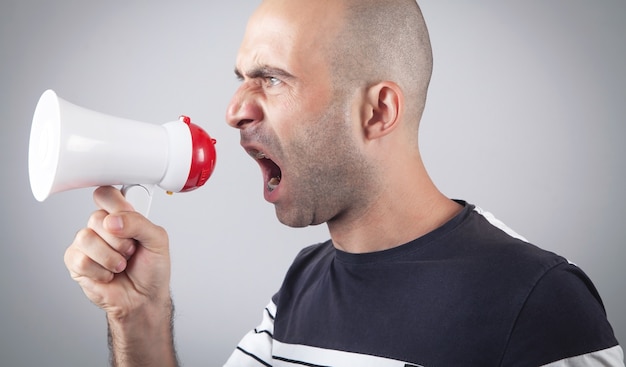 Caucasian man screaming with megaphone.