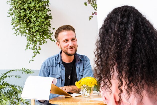 Caucasian man sitting and smiling at unrecognizable curly-haired woman.