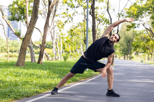 Caucasian man in sportswear stretching body and warm up before jogging exercise at public park in the morning Healthy guy athlete enjoy outdoor lifestyle sport training running workout in the city