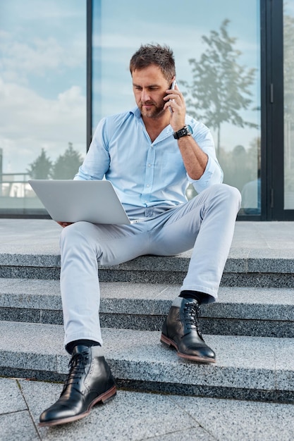 Caucasian man studying business proposal using laptop while sitting on the street