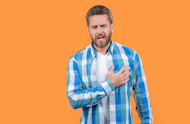 Caucasian man suffering from heartache isolated on yellow background copy space