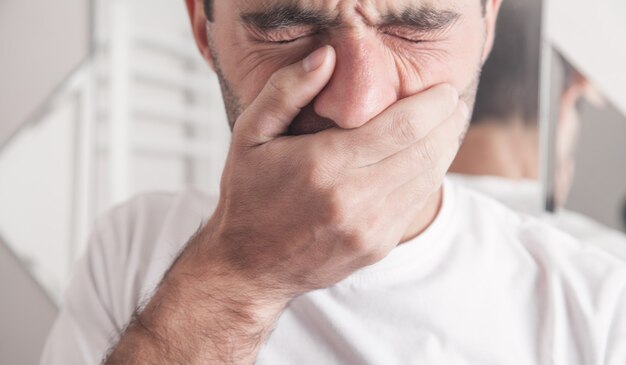 Caucasian man suffering toothache in bathroom.