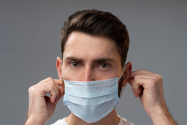 Caucasian man taking on protective mask while safe against coronavirus infection Covid 19 pandemic concept