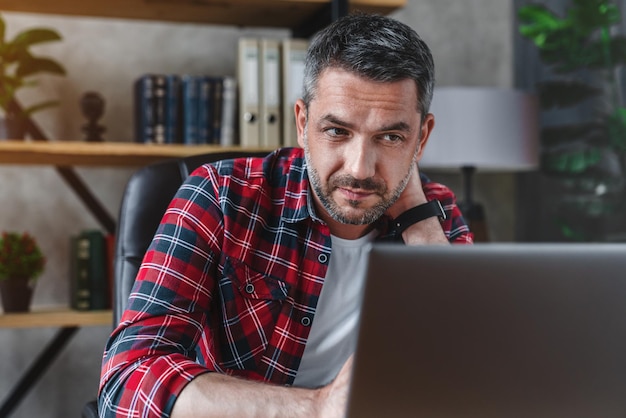 Caucasian man touching neck due to tiredness from work for a
long time at his home