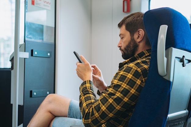 Кавказский мужчина путешествует на поезде с помощью смартфона