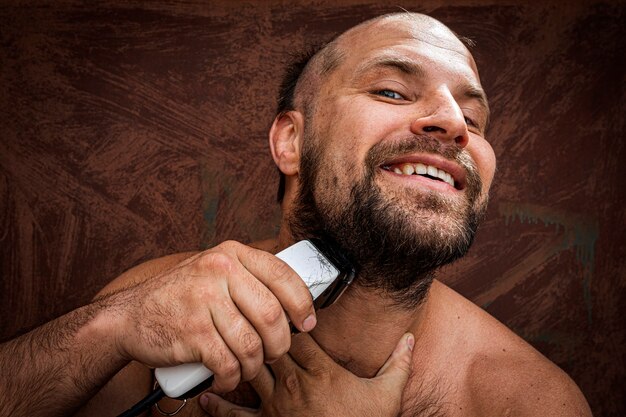 Photo caucasian man trying to shave with an electric razor.