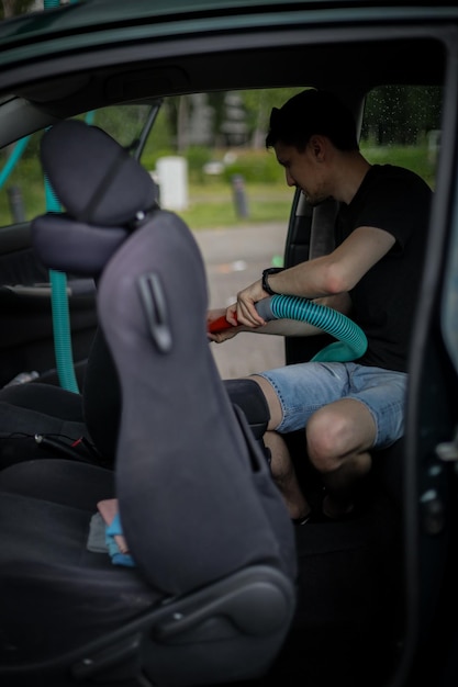 Caucasian man vacuuming a car at a gas station