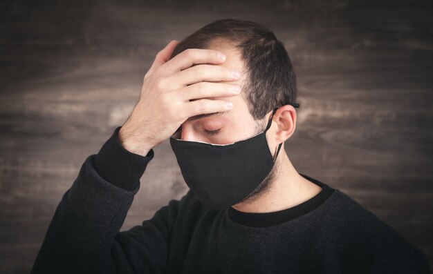 Caucasian man wearing black face mask.