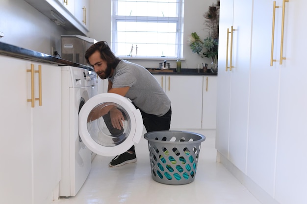 Caucasian man wearing gray tshirt and doing laundry