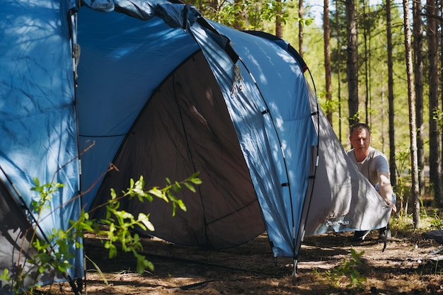 Caucasian man wearing a hat putting up a tent Family camping concept