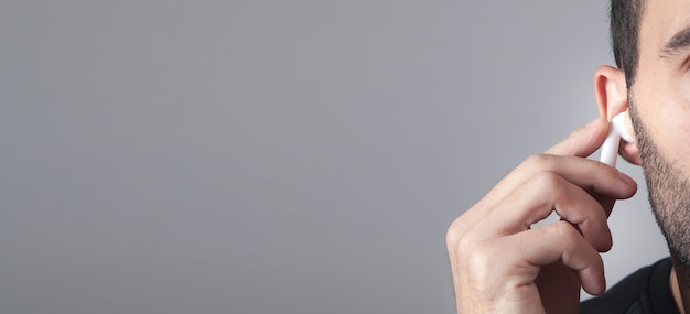 Caucasian man wearing white wireless earphone.