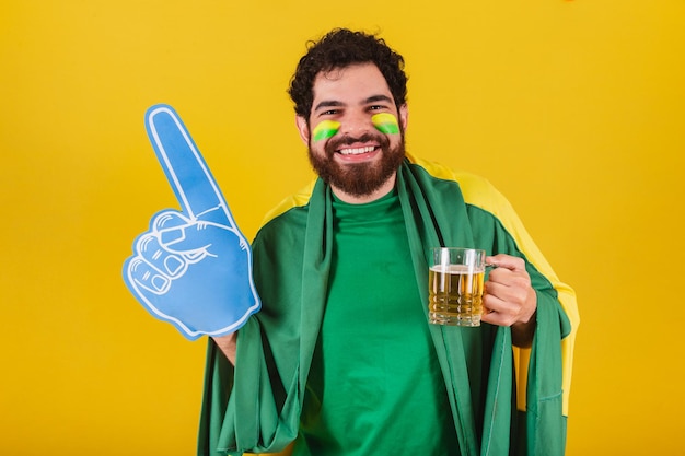 Caucasian man with beard brazilian soccer fan from brazil\
celebrating while having a beer