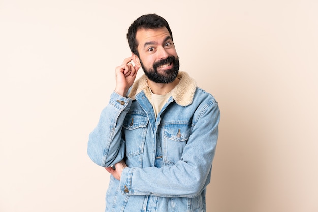 Caucasian man with beard over isolated background having doubts