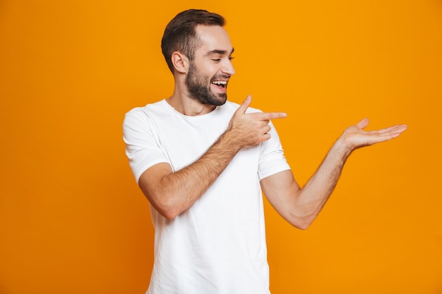 caucasian man with beard and mustache showing copyspace on palm while standing, isolated on yellow