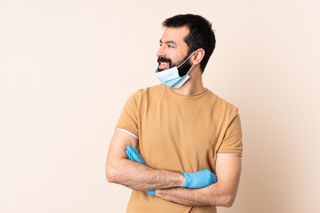 Caucasian man with beard protecting with a mask and gloves over wall looking side