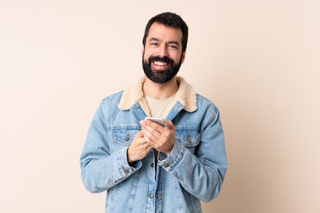 Caucasian man with beard sending a message with the mobile