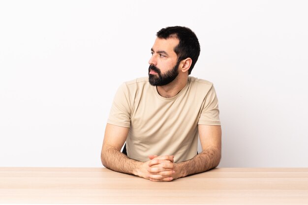 Caucasian man with beard in a table looking to the side