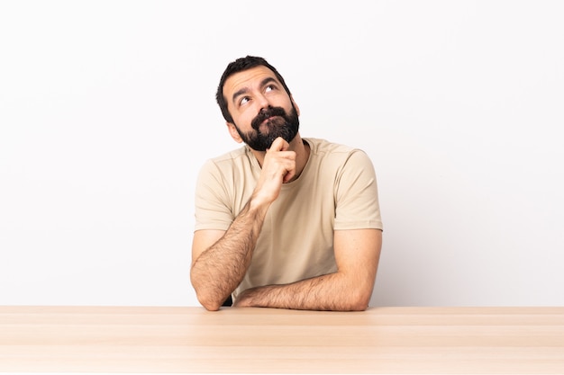 Caucasian man with beard in a table and looking up