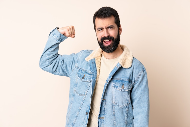 Photo caucasian man with beard over wall doing strong gesture