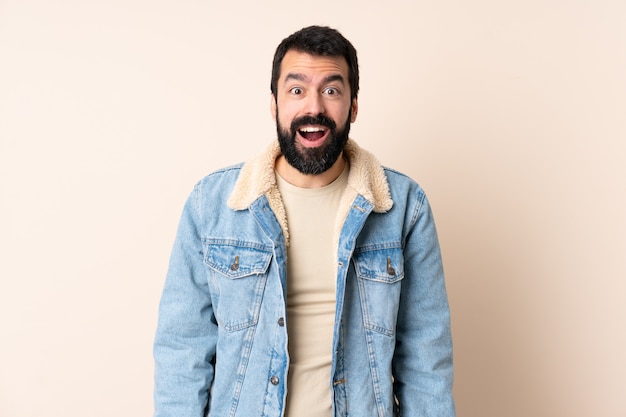 Caucasian man with beard over wall with surprised facial expression