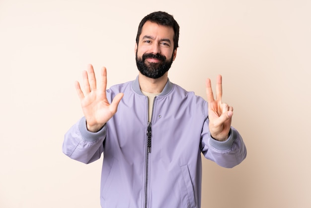 Caucasian man with beard wearing a jacket counting seven with fingers